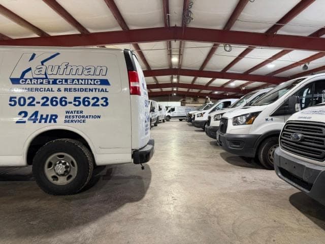 Kaufman Carpet Cleaning's fleet of white vans parked inside the company garage